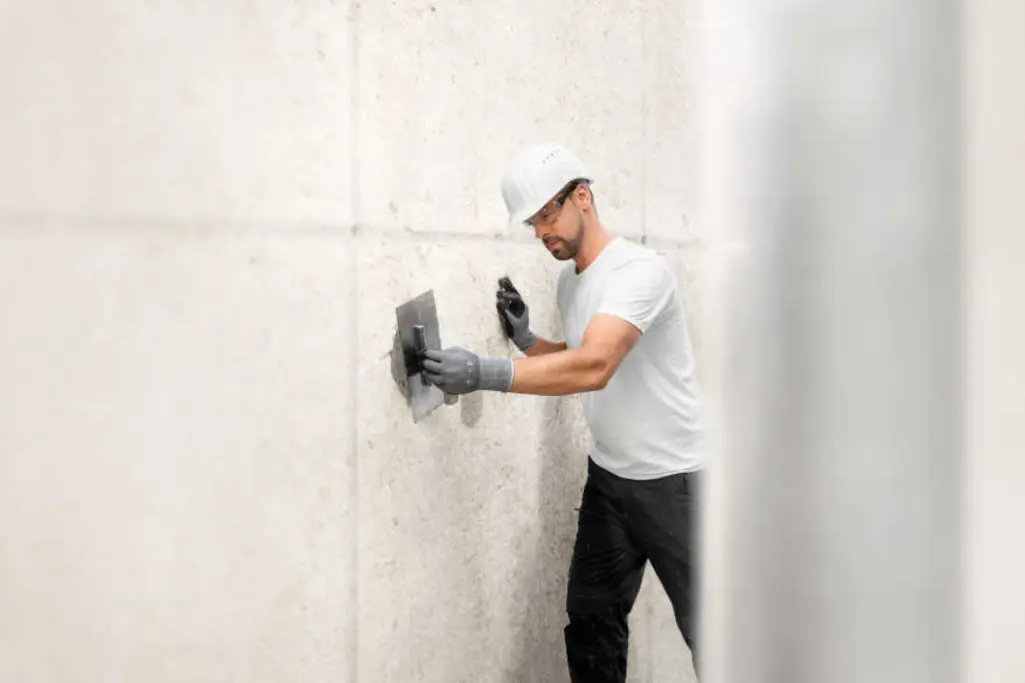 Handwerker glättet Betonwand zur Betonsanierung.