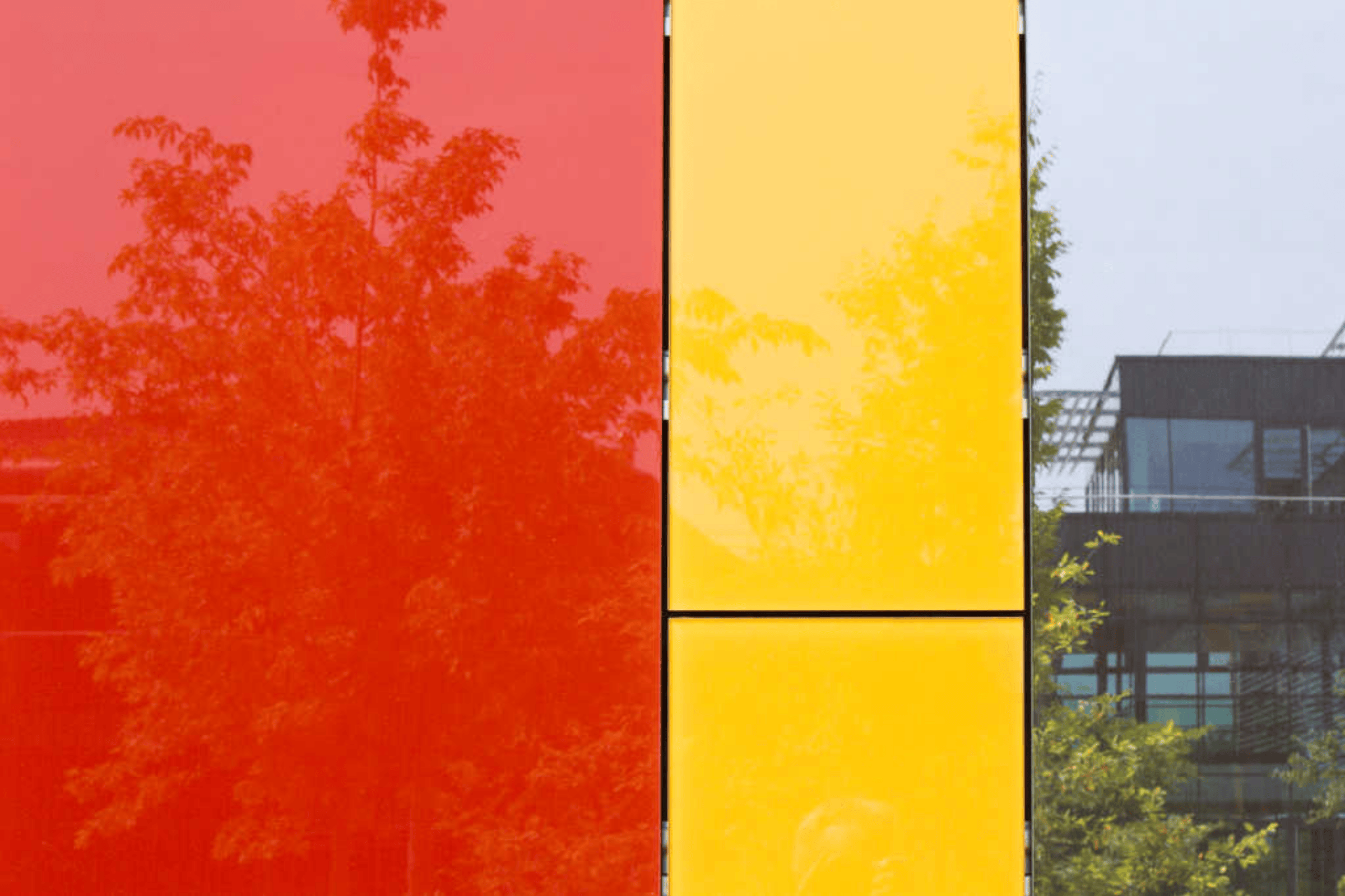 Sto-Glasfassade mit hochglänzenden Paneelen in Rot und Gelb