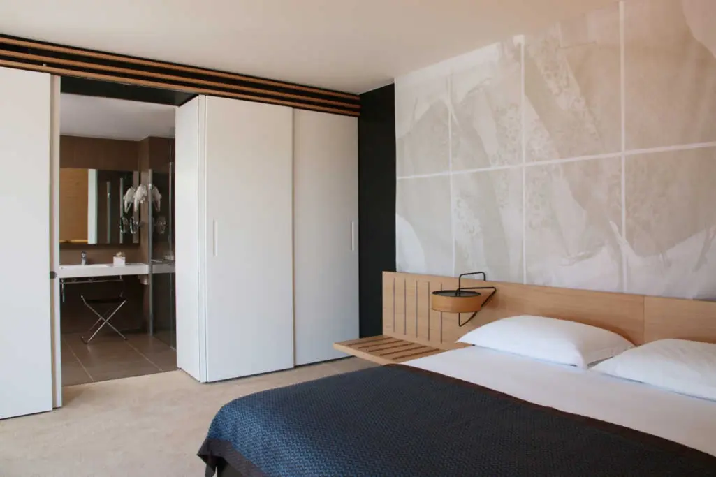 Modernes Hotelzimmer mit Holzbettrücken und abstrakter Wandgrafik.