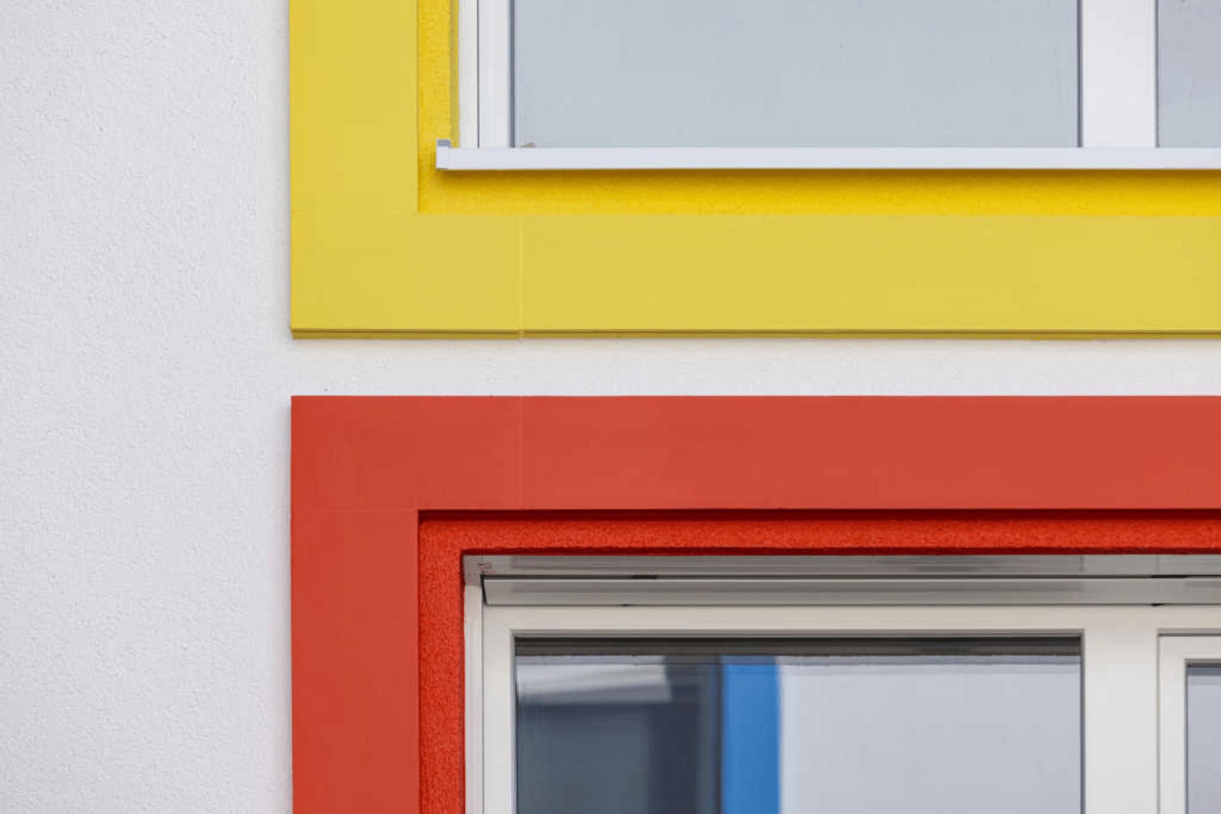 Fassadendetail mit StoDeco-Formteilen: gelber und roter, plastisch hervortretender Fensterrahmen. 