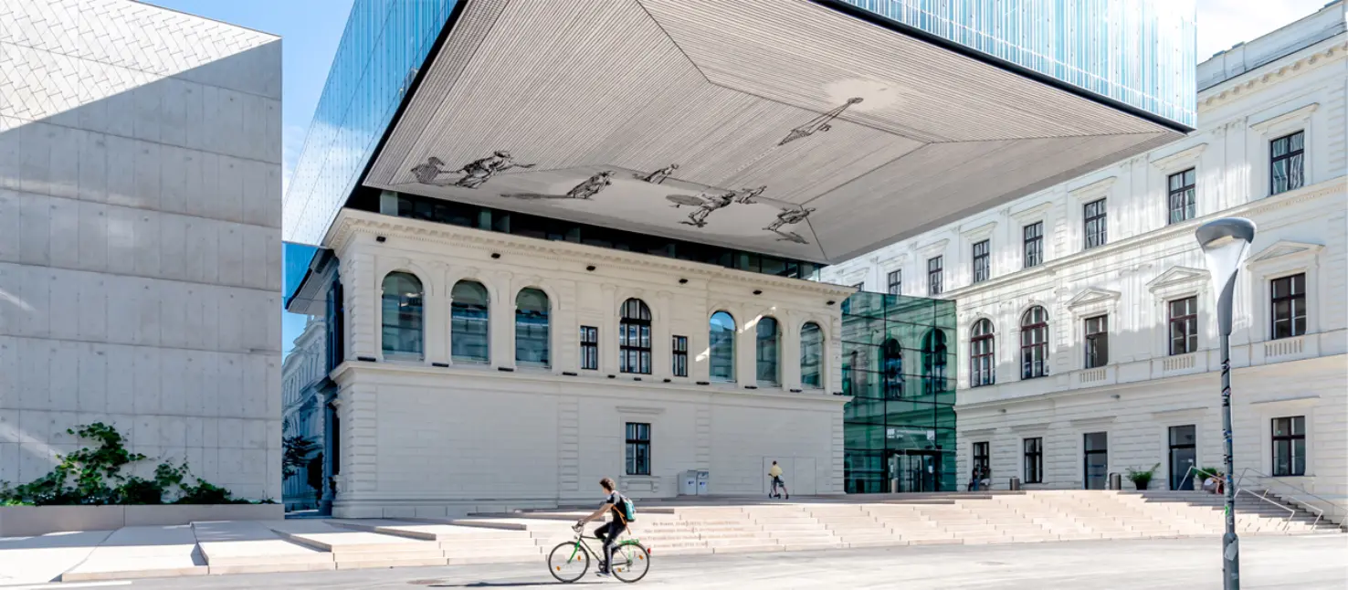 Uni-Bibliothek Graz: Historischer Bau mit schwebendem Glaskubus und Freitreppe.