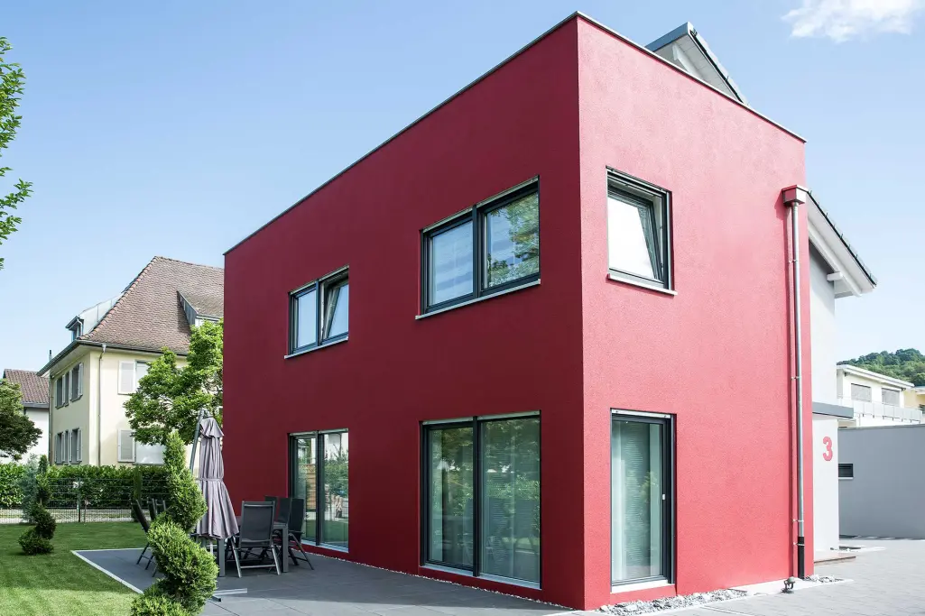 Fassadenfarbe mit SunBlock Technologie. Einfamilienhaus mit roter Hausfassade 