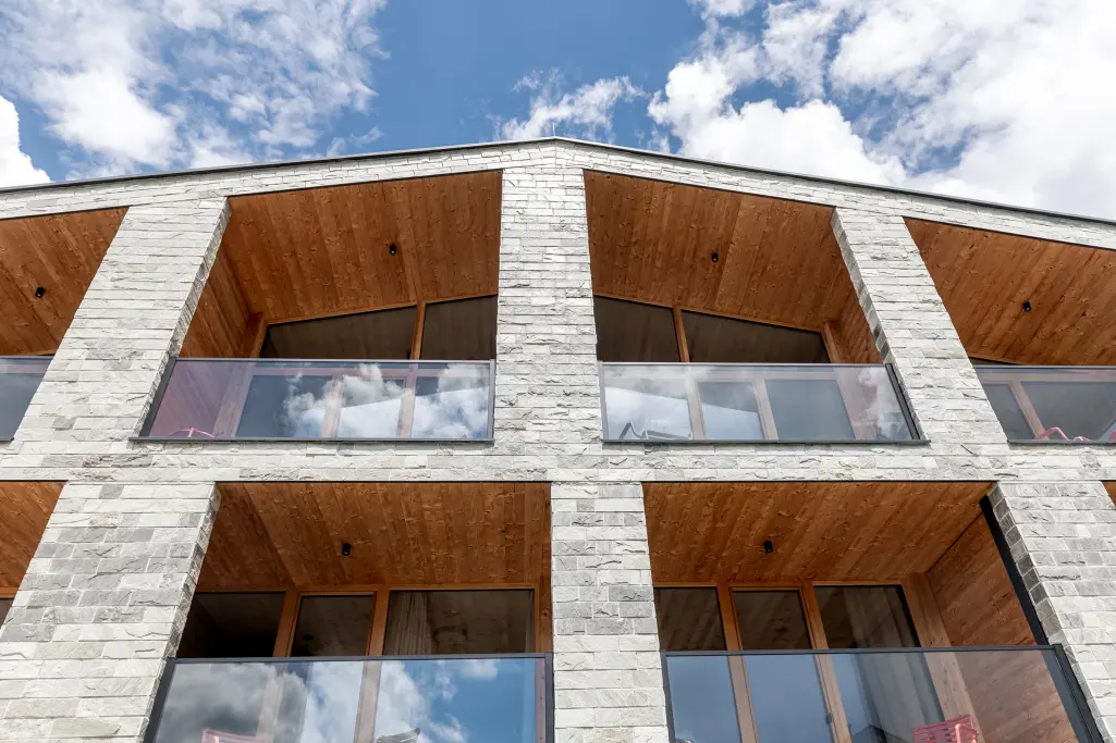 Steinverkleidete Berglodge mit Holzloggien und Glasbrüstungen.