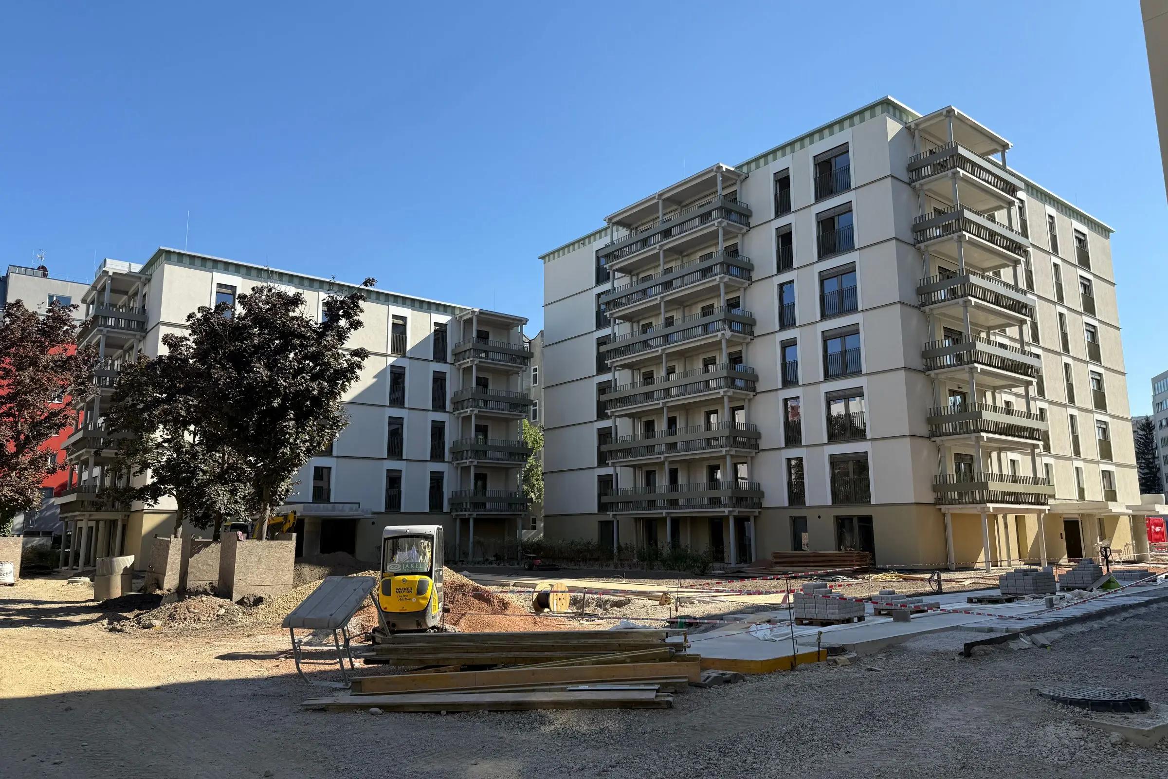 Zwei Wohngebäude im Leopoldquartier Wien mit heller Fassade und Balkonen, umgeben von Baustelle